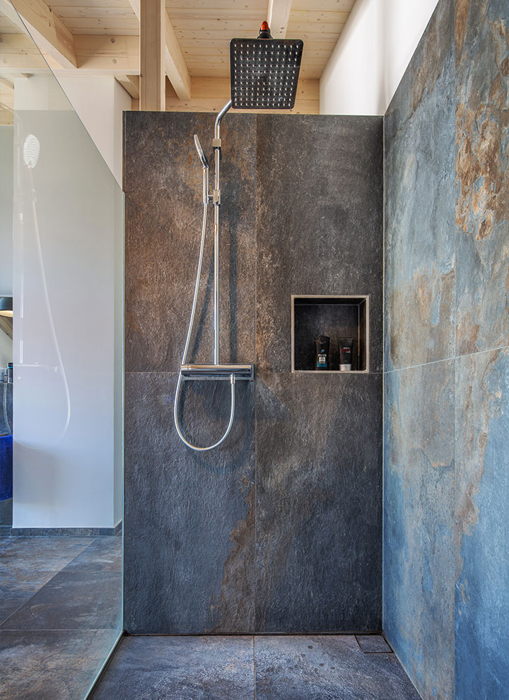 Dusche mit dunklen Wandfliesen und eingelassener Ablage in Haus Leitensee