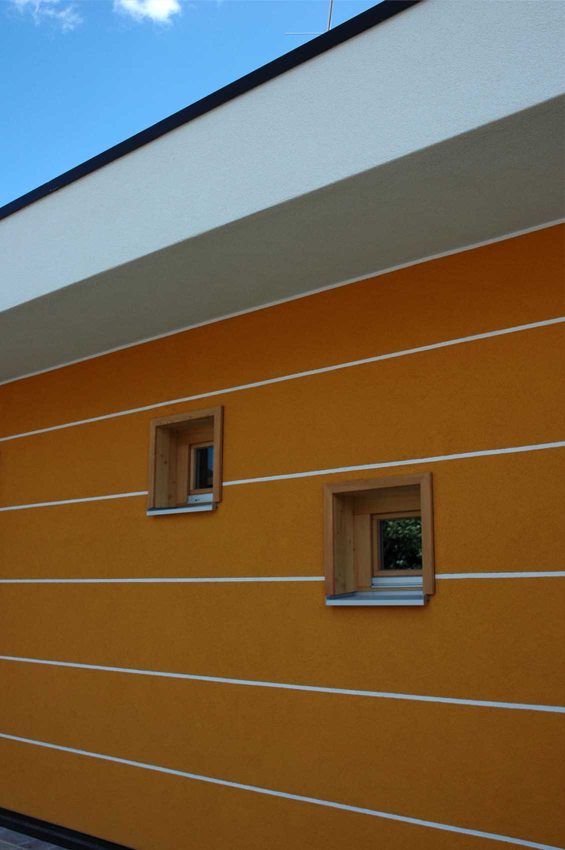 Orangefarbenes Fassadendetail von Haus Gardasee mit schmalen Fenstern