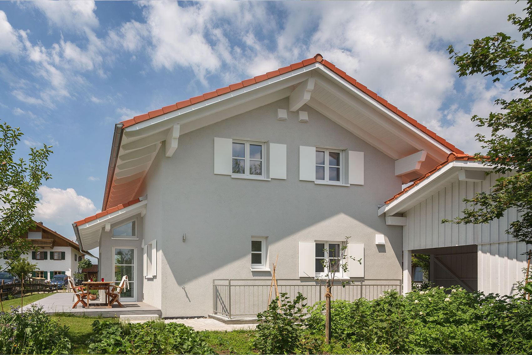 Heller Giebel von Haus Ulmensee mit Fenstern und rotem Dach