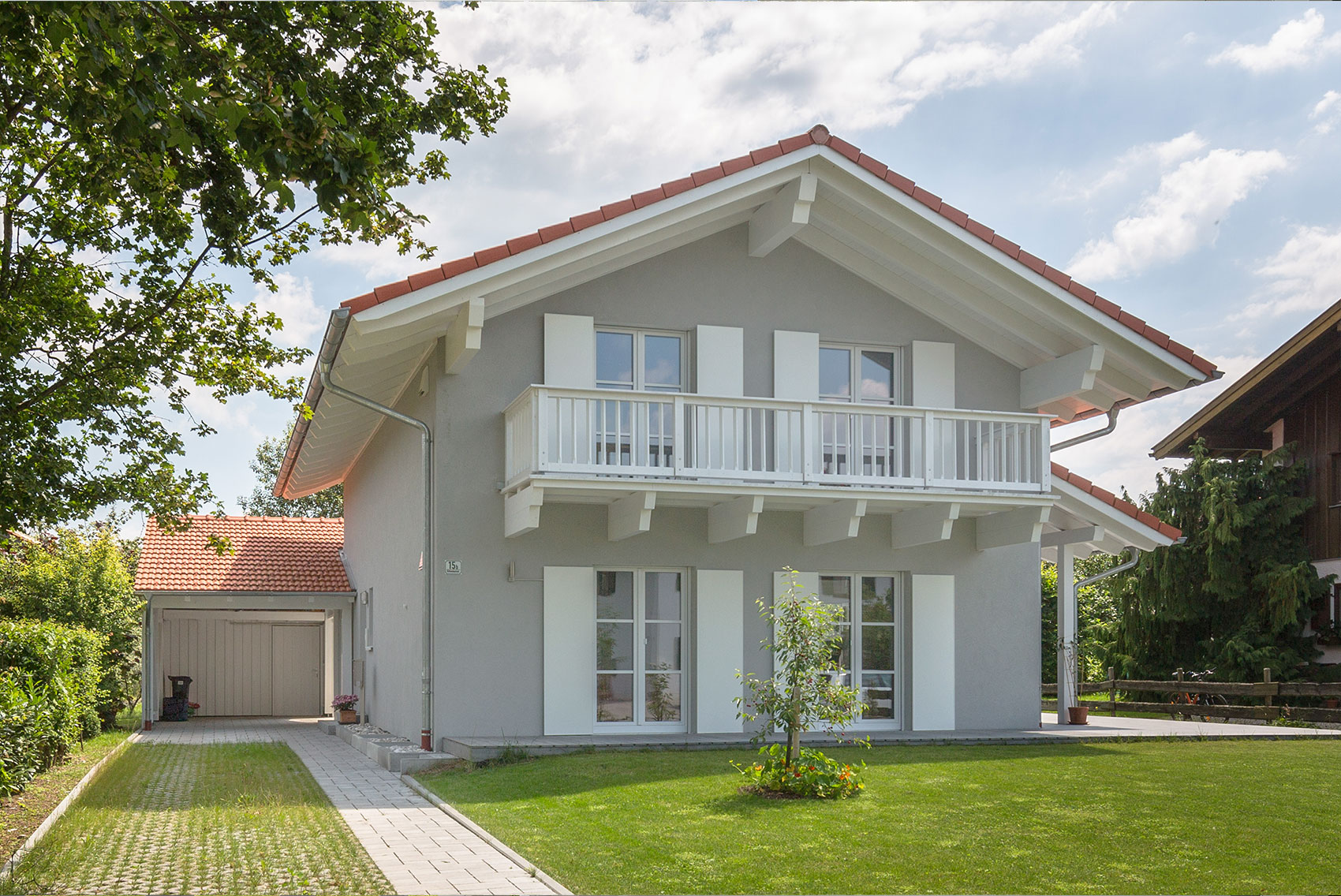 Giebelseite von Haus Ulmensee mit weißem Balkon und großen Fenstern