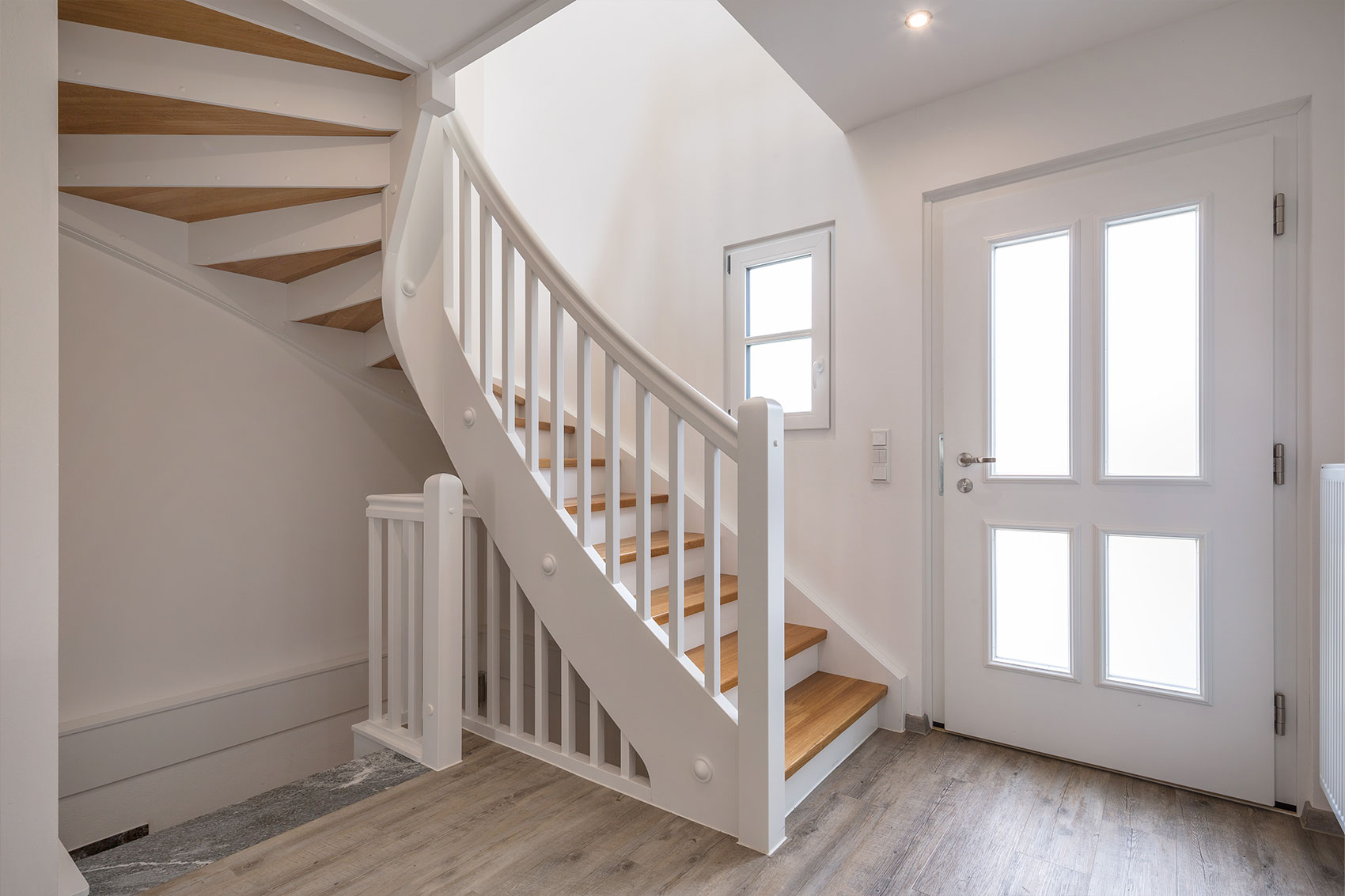 Weiße Holztreppe im Eingangsbereich von Haus Ulmensee