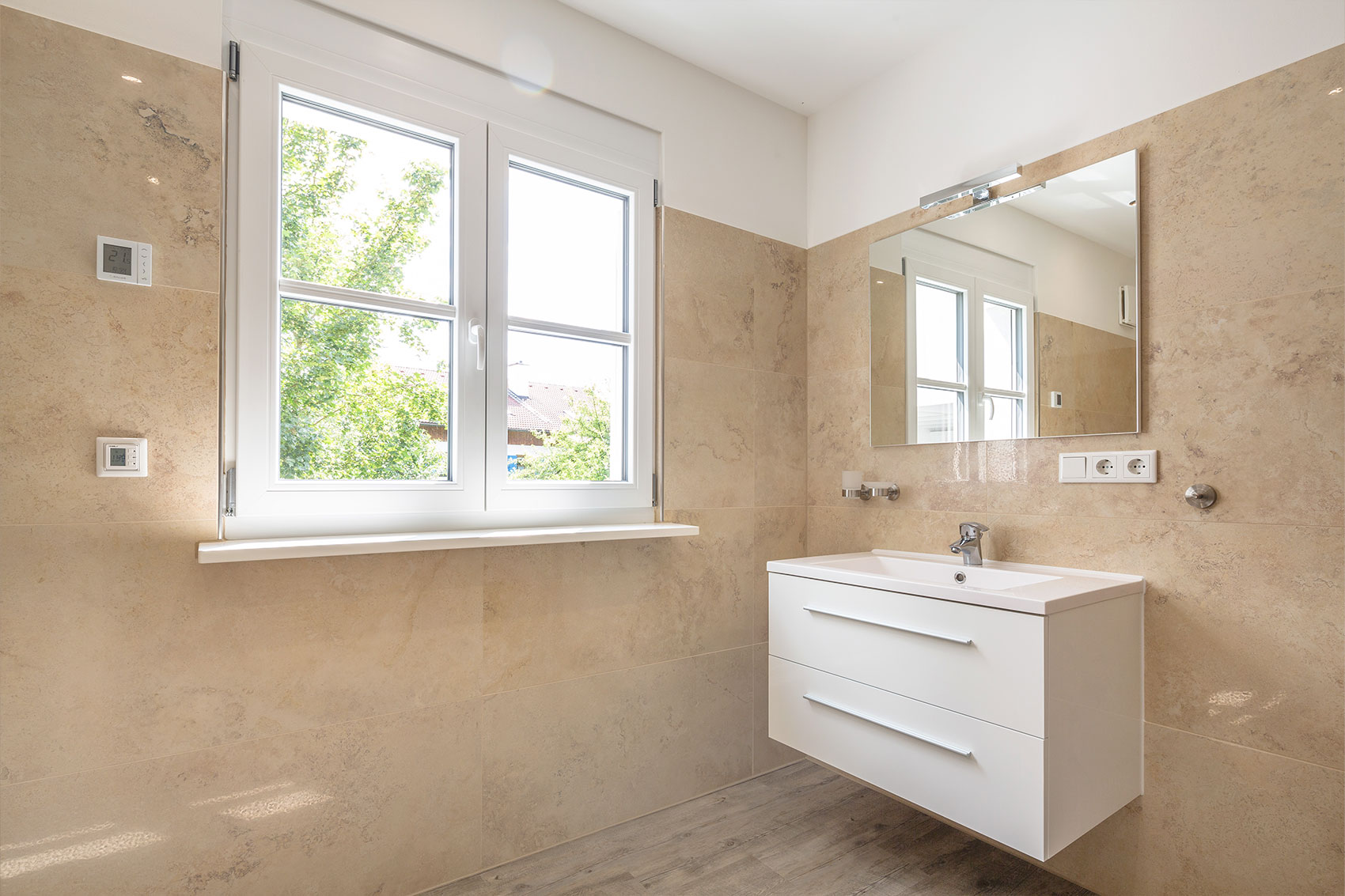 Helles Badezimmer mit Fenster und weißem Waschtisch