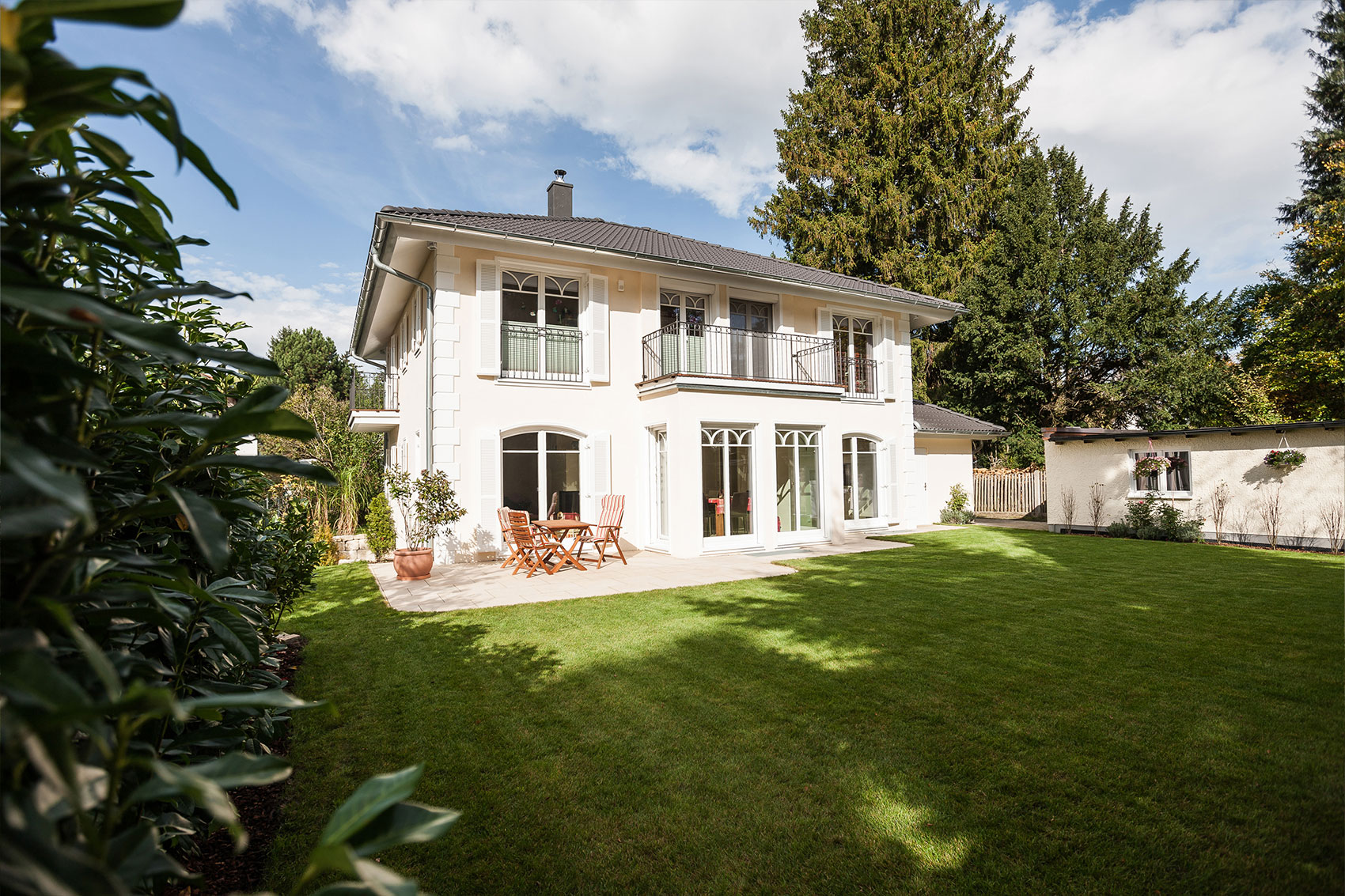 Villa Victoria · Haus und Garten Gartenansicht der Villa Victoria mit Rasenfläche und sonniger Terrasse