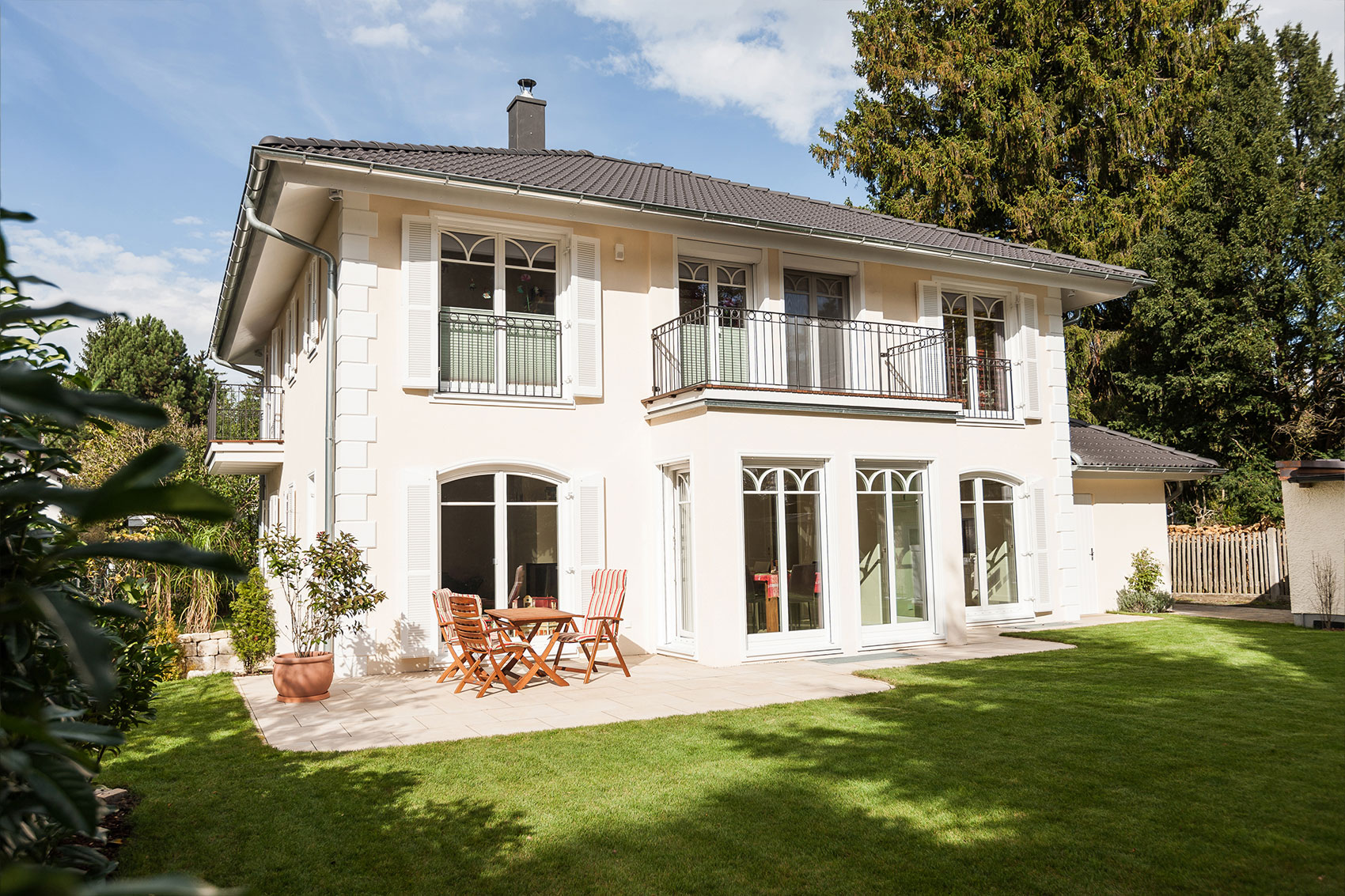 Villa Victoria mit heller Putzfassade, Balkon und Terrasse zum Garten