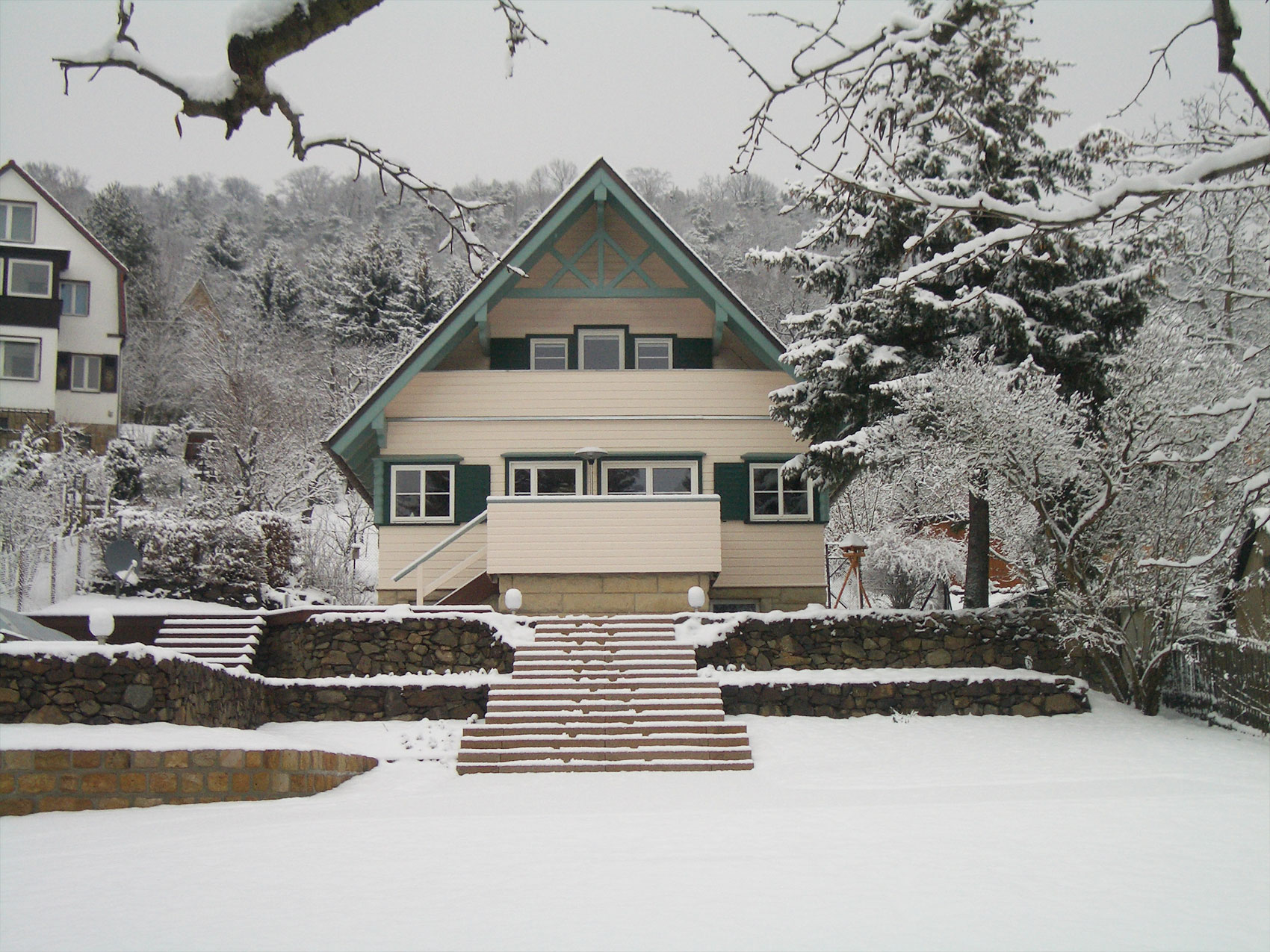 Holzhaus mit grünem Giebel und verschneitem Garten