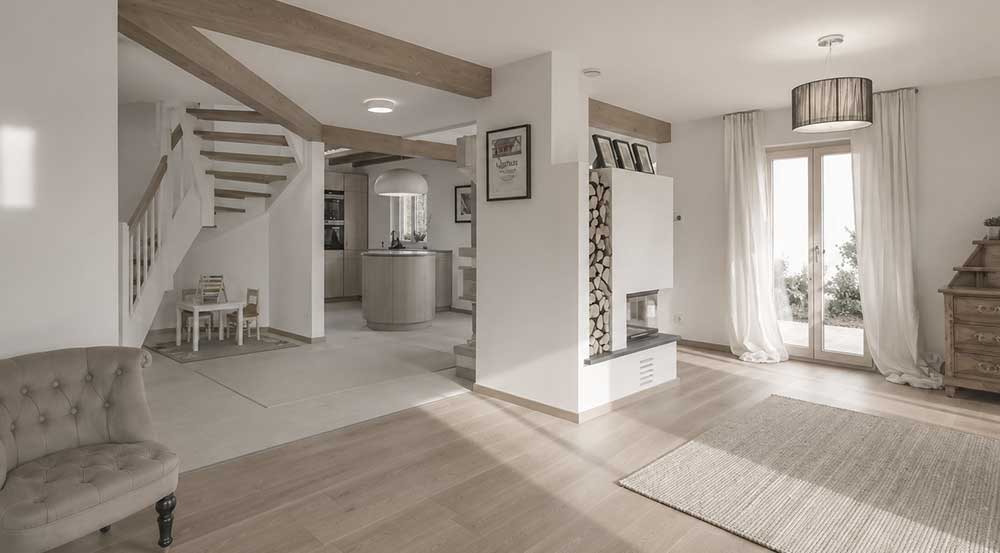 Holzhaus Poing · Wohnbereich mit Kamin Heller Wohnbereich im Holzhaus mit Kamin und sichtbaren Deckenbalken