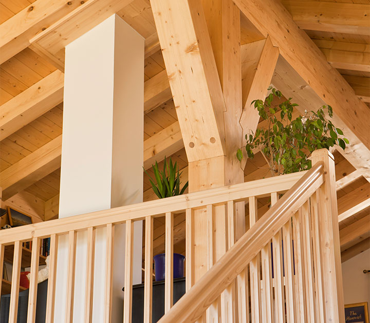 Sichtbare Holzbalken und Holzgeländer im Innenraum eines Holzhauses