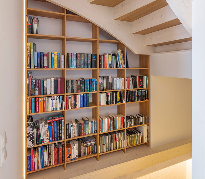 Bücherregal unter einer Holztreppe in einem hellen Wohnbereich