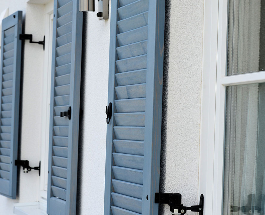 Blau-graue Fensterläden an einer hellen Fassade