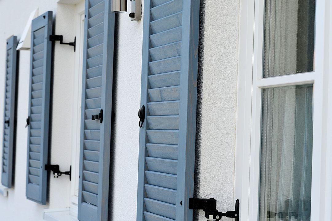 Blau-graue Fensterläden an einer hellen Fassade