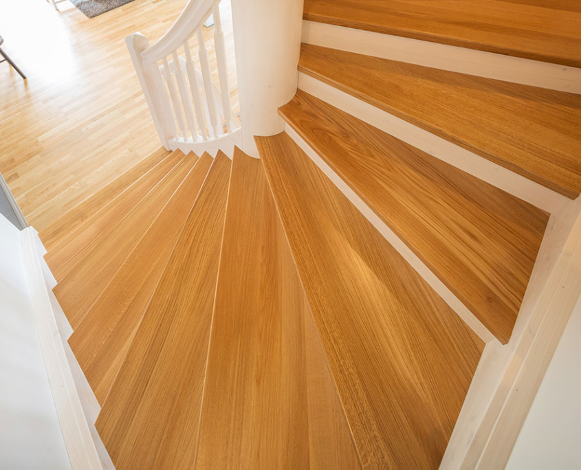 Blick auf eine Holztreppe mit hellen Stufen und weißem Geländer