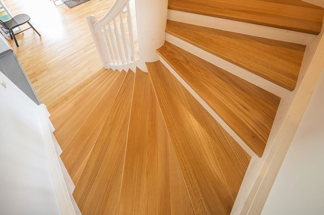 Blick auf eine Holztreppe mit hellen Stufen und weißem Geländer