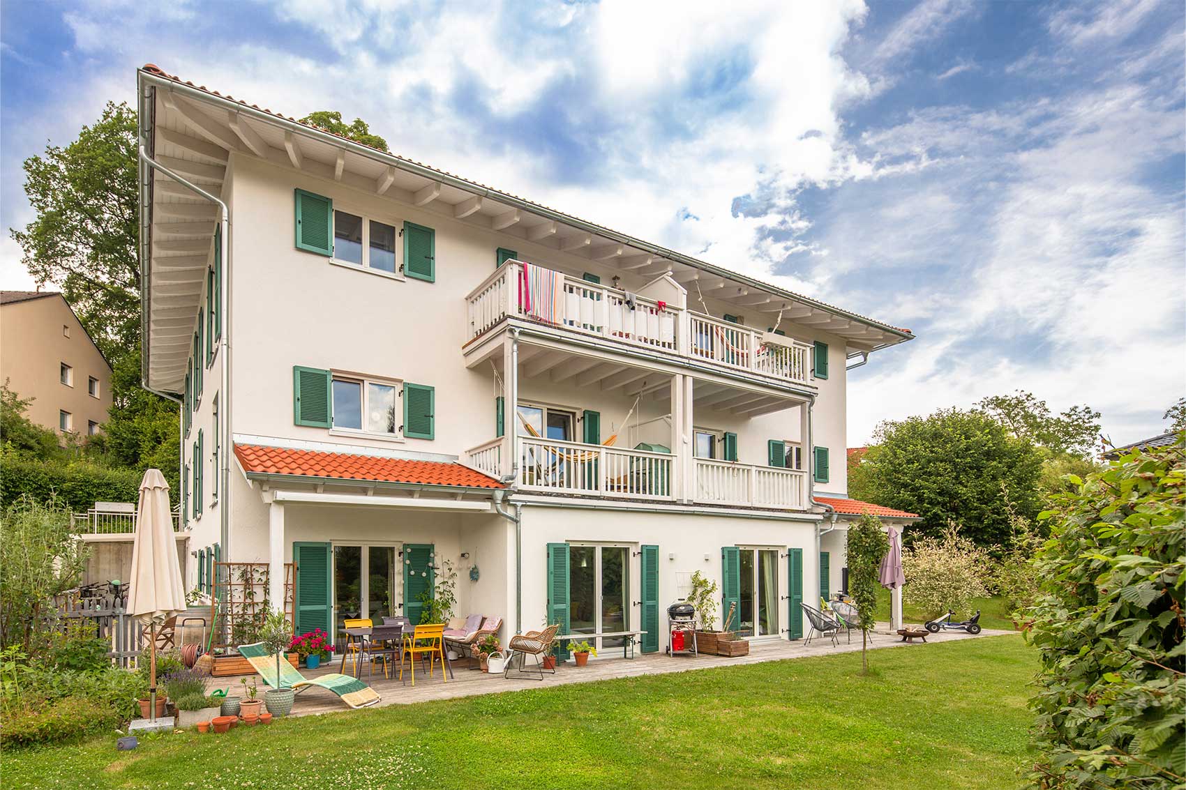 Mehrfamilienhaus Klostersee mit grünen Fensterläden und übereinanderliegenden Balkonen