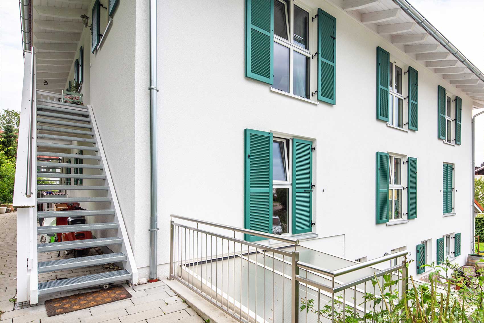 Hausperspektive - Fenster mit grünen Klappläden an der Fassade des Mehrfamilienhauses Klostersee