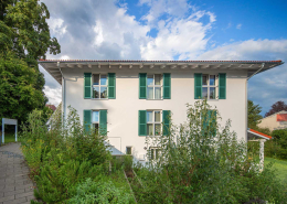 Helle Fassade des Mehrfamilienhauses Klostersee mit grünen Klappläden