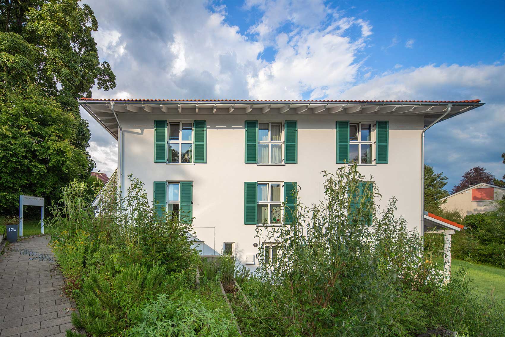 Helle Fassade des Mehrfamilienhauses Klostersee mit grünen Klappläden