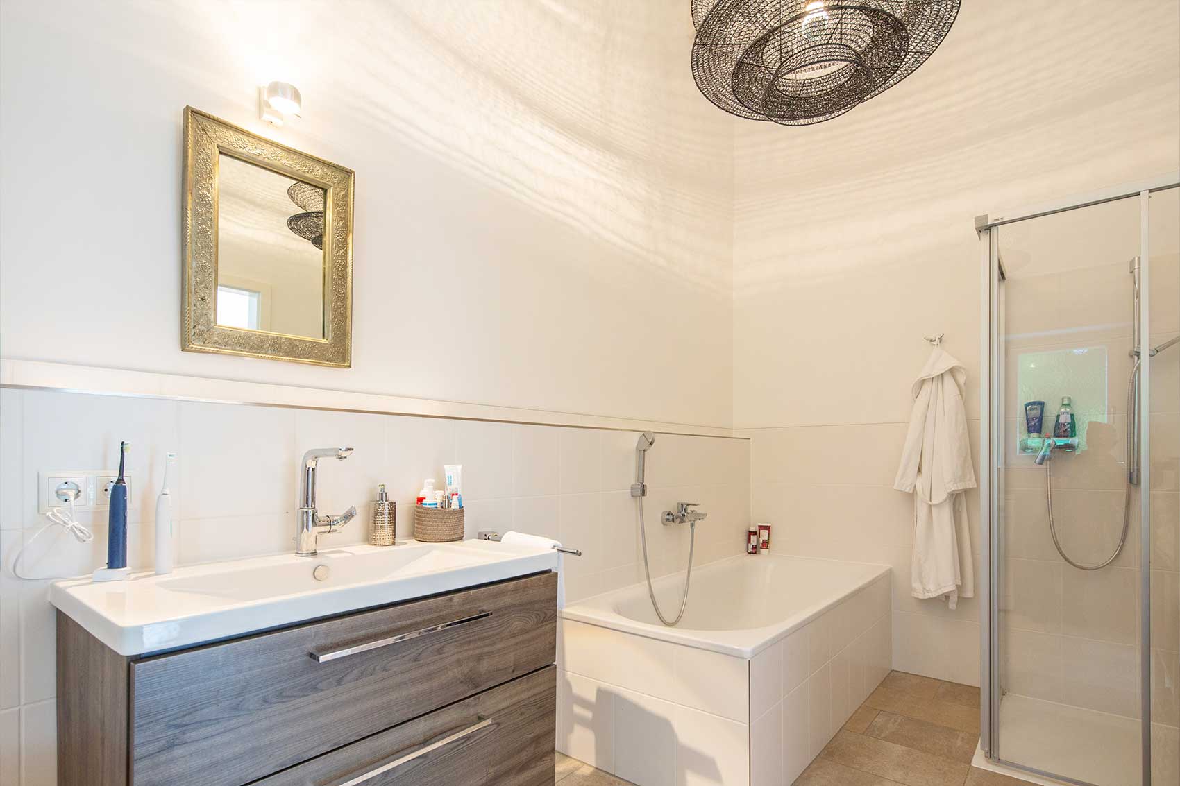 Helles Badezimmer in Haus Klostersee mit Dusche, Badewanne, Spiegel und Waschtisch
