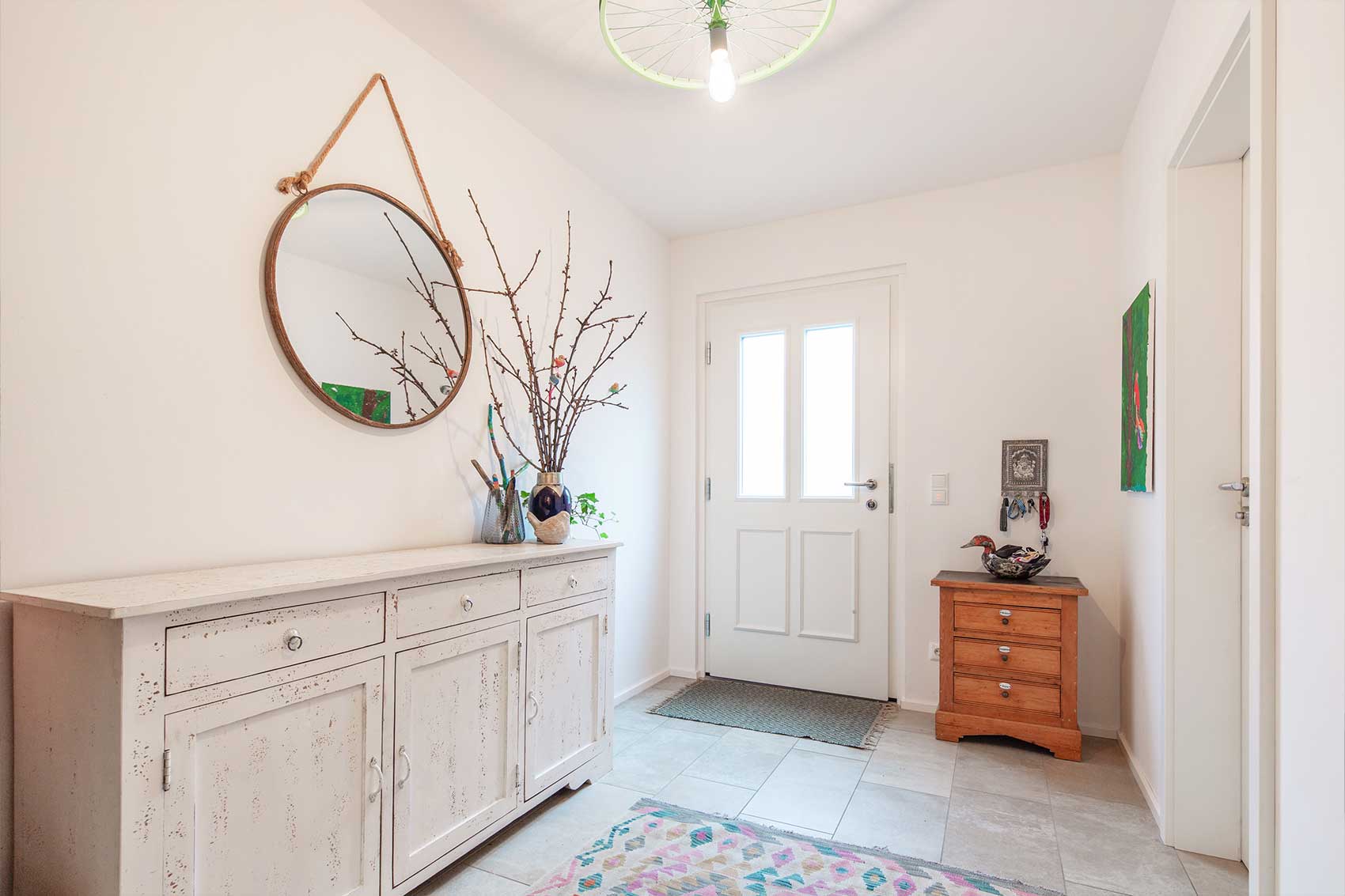 Eingangsbereich von Haus Klostersee mit rundem Spiegel und heller Tür