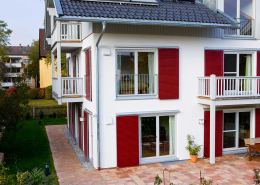 Fenster und rote Schiebeläden an der Fassade von Haus Langwiedersee