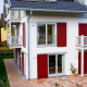 Fenster und rote Schiebeläden an der Fassade von Haus Langwiedersee