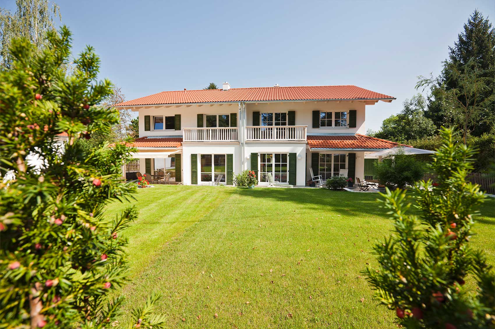 Doppelhaus Waldsee in Holzrahmenbauweise mit rotem Satteldach und großen Fenstern zum Garten