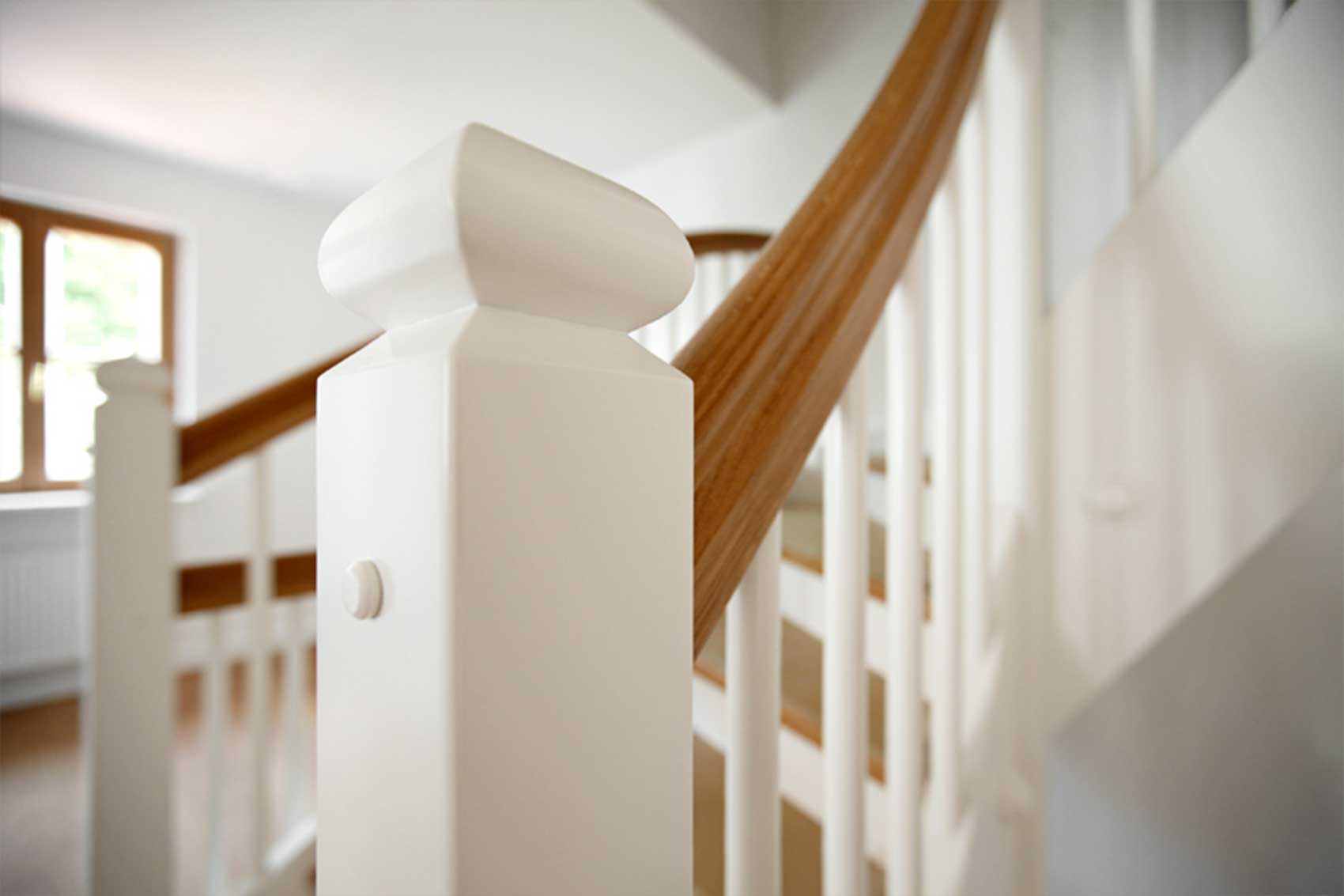 Detail des weißen Treppengeländers mit Holzhandlauf in Haus Wörthersee