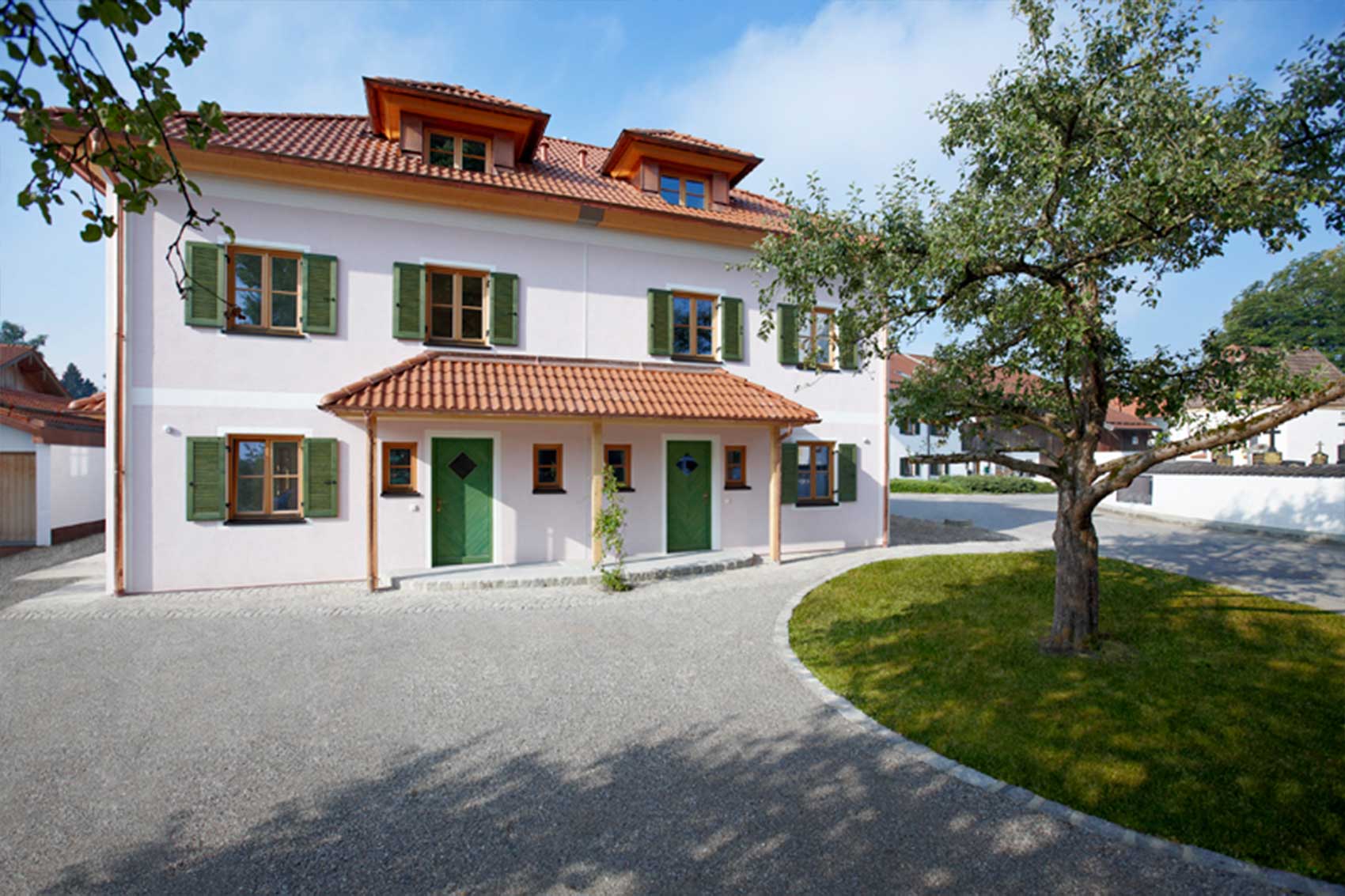 Eingangsseite des Doppelhauses Wörthersee mit grün gestrichenen Fensterläden