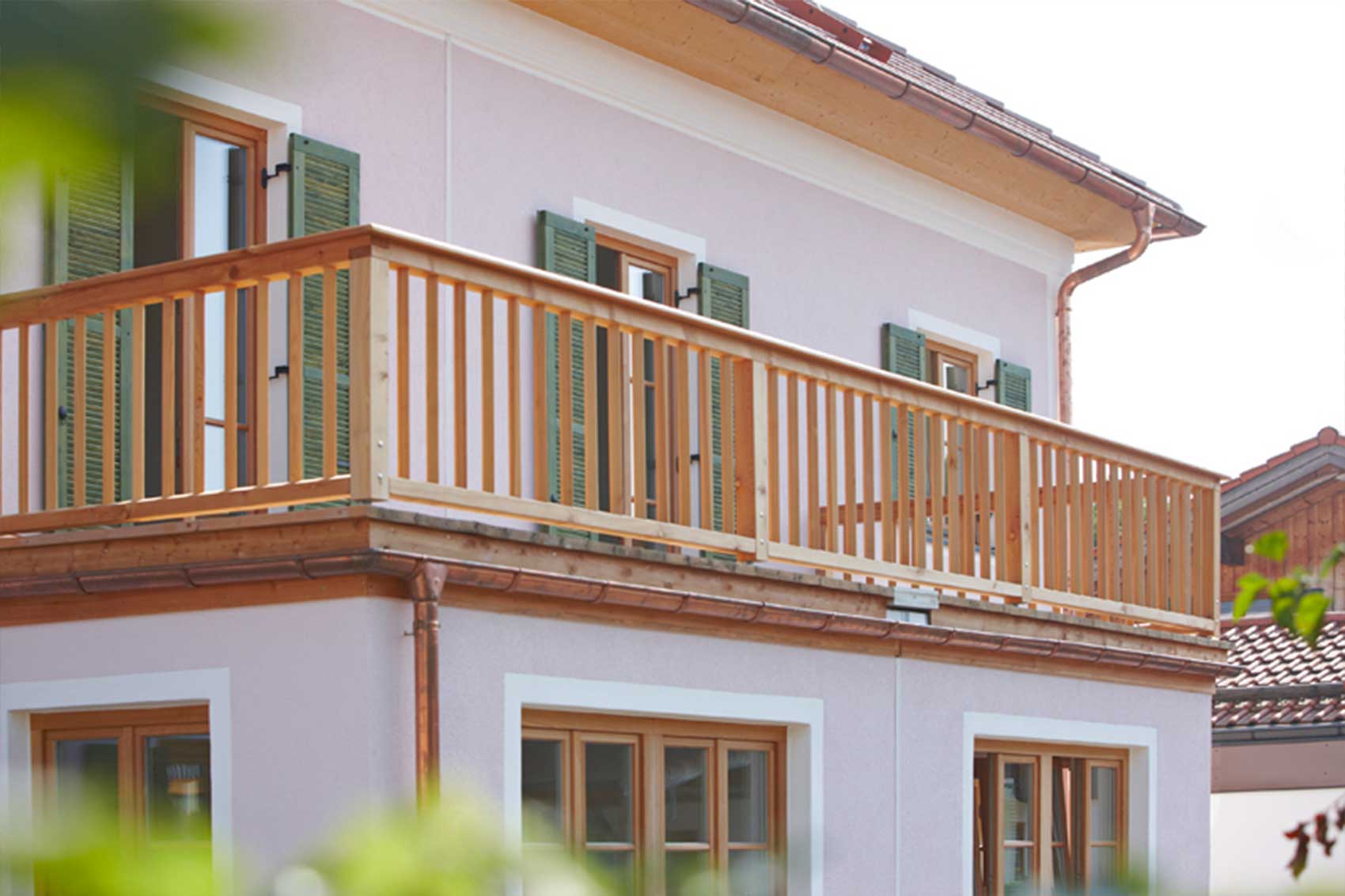 Holzbalkon an der hellen Fassade von Haus Wörthersee