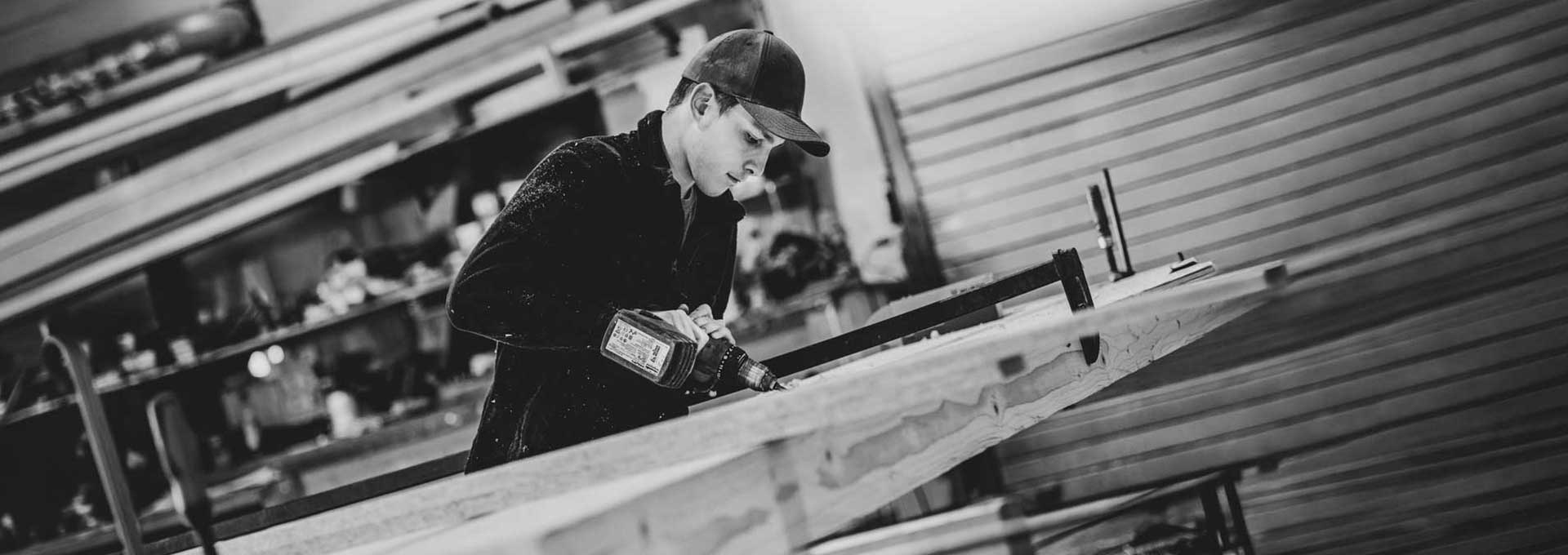 Holzverarbeitung · Handwerk Schwarz-Weiß-Aufnahme eines Handwerkers bei der Holzbearbeitung
