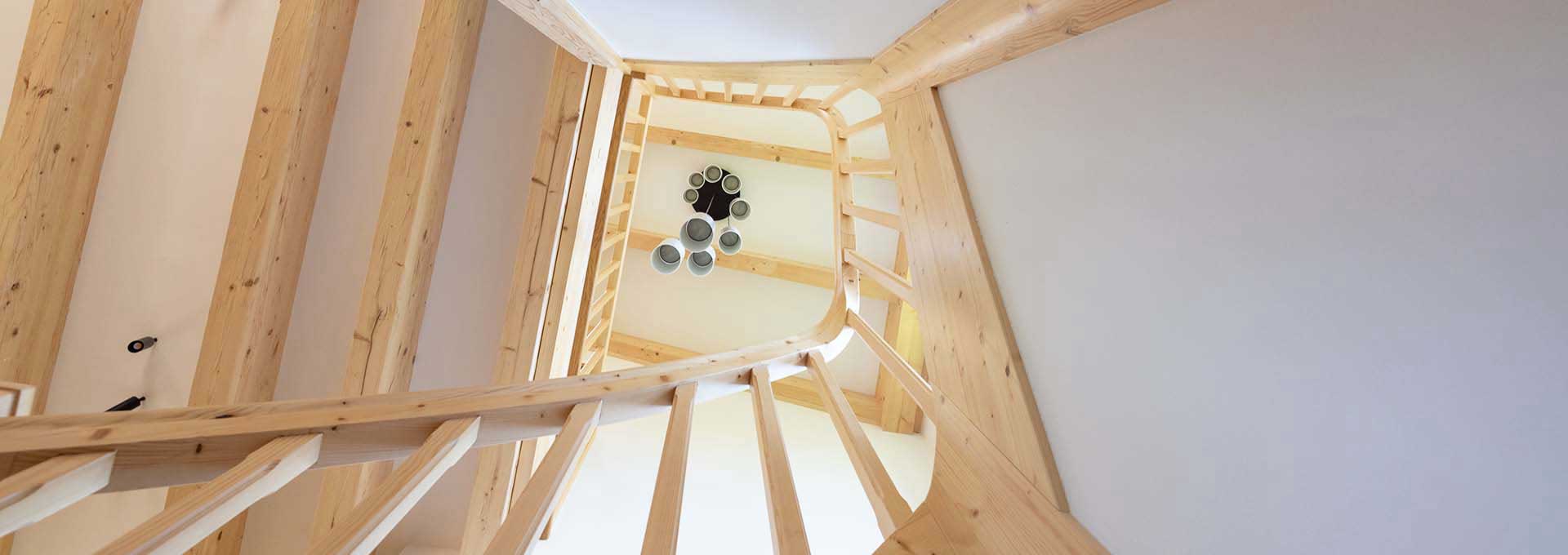 Holzbau Treppe · Sichtbare Holzkonstruktion Treppenansicht - Blick nach oben auf eine Konstruktion aus hellen Holzbalken