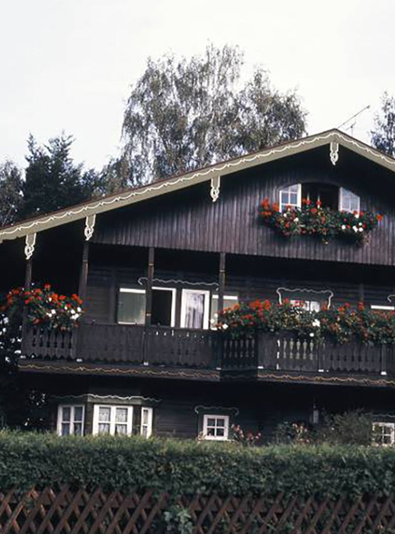 Historisches Holzhaus · Außenansicht Dunkles Holzhaus mit Blumenschmuck an den Balkonen