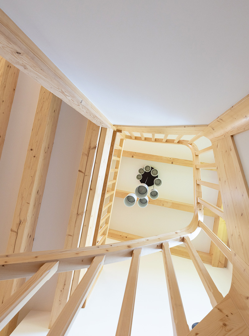 Holzbau Treppenhaus · Blick nach oben Blick nach oben im Treppenhaus durch eine Holzkonstruktion mit sichtbaren Balken