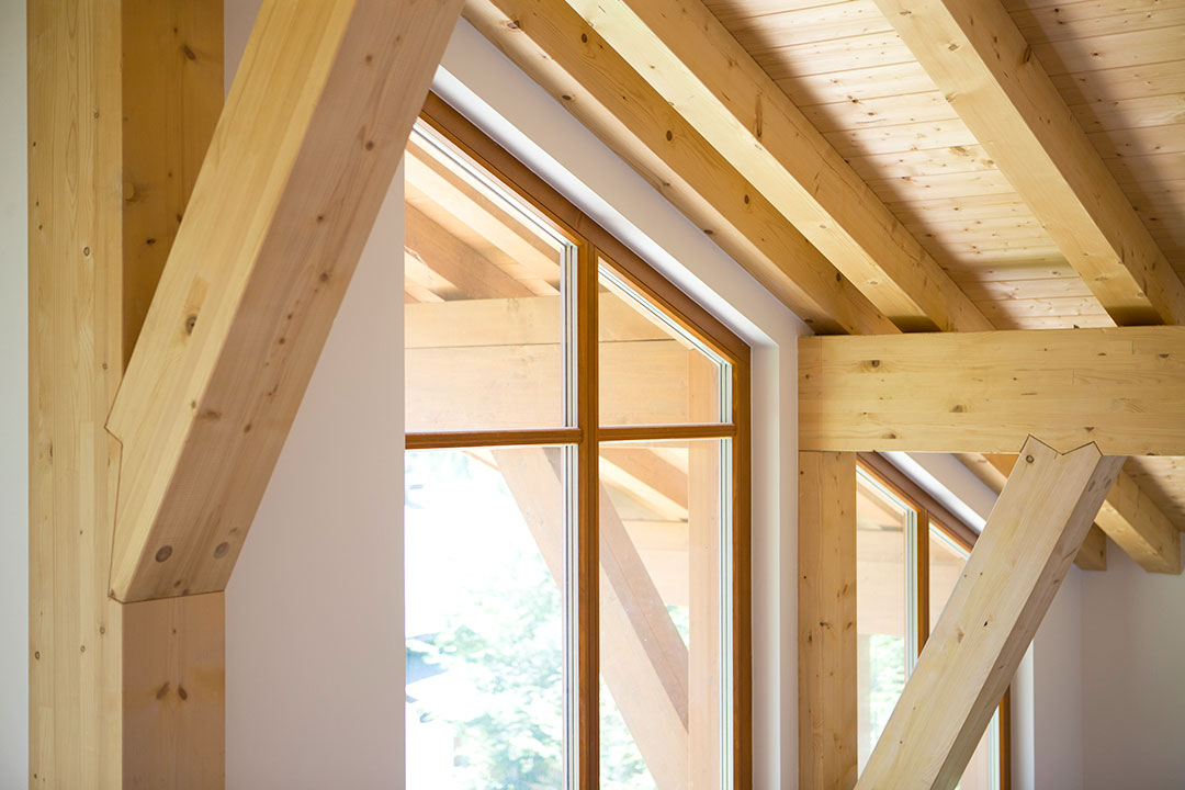 Ausbaustufen | Holzbauweise Großes Holzfenster und sichtbare Dachbalken im Innenraum